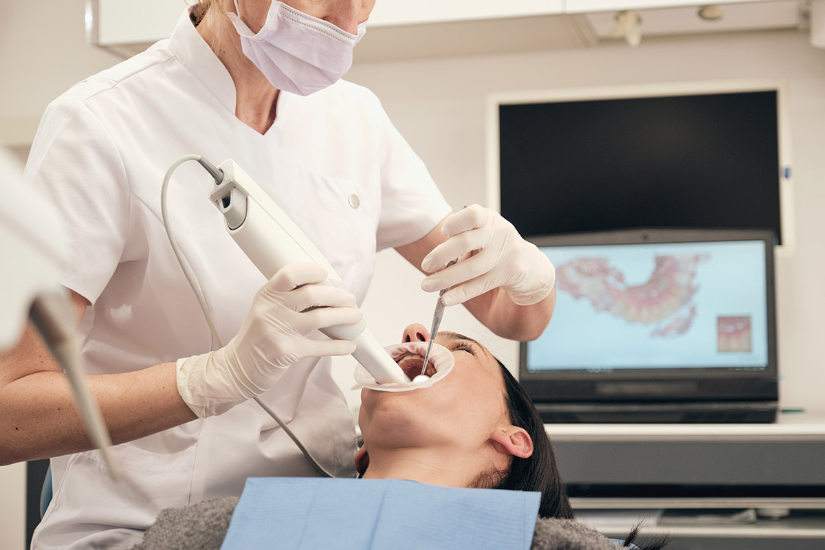 Female dentist scanning teeth of woman